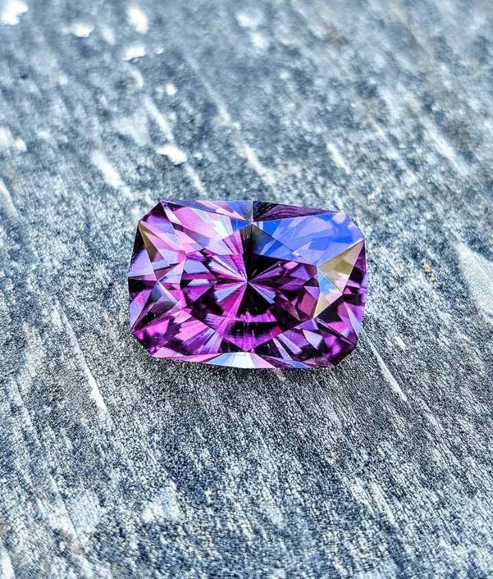 A color change sapphire resting elegantly on a polished wooden surface.
